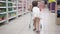 Funny cute child pushing shopping cart in supermarket