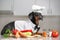 Funny cute dachshund dog, in a cap and a suit of the chef, in the kitchen among vegetables and various cookware