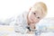 Funny cute little child in pyjamas with blonde hair lies on a bed