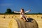 Funny cute little girl posing on the haystack in summer field