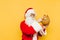 Funny and cute Santa Claus is holding a stuffed reindeer toy in his hand, touching a nose of the toy. Amusing Santa is playing