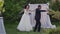 Funny dance of joyful African American newlyweds in summer garden at wedding altar. Wide shot of cheerful bride in dress