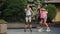 Funny dance of two young girls roller skating in a city park