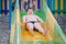Funny delightful fat little caucasian boy in swimming trunks roll down on water slide during summer leisure vacation in amusement