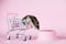 Funny Djungarian hamster in children`s empty shopping cart runs away and looking for food in bowl on a pink background