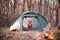 Funny dog in a knit sweater sits in a tent by the campfire.