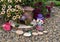 Funny dollhouse with small watering can and petunia flowers in the garden