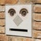 A funny doorbell panel on old brick wall and mail post box with letter. Fake face concept