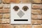 A funny doorbell panel on old brick wall and mail post box with letter. Fake face concept