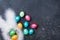 Funny Easter background. Confetti, bunny ears and colorful Easter eggs on black table top view. Copy space for text.