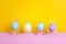 Funny Easter eggs with faces on bird legs on yellow background.
