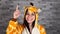 A funny emotional woman in a big pajamas of giraffe smiles and raises her index finger up on a brick background. A woman