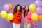 Funny european african american women friends in sweaters isolated on violet purple background. Birthday holiday party