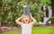 Funny excited child waters plants in backyard garden with watering can.