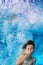Funny face portrait of smiling child swimming underwater in pool
