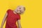 Funny fair-haired boy in red t-shirt on bright yellow background. Child fooling around. Copy space