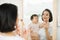 Funny family at home. Mother and her child girl are doing your makeup and having fun near mirror. Baby girl explores mother`s