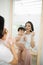 Funny family at home. Mother and her child girl are doing your makeup and having fun near mirror. Baby girl explores mother`s