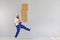 Funny fat bearded delivery courier loader man in a blue uniform with a cardboard box on a gray background.