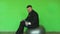 Funny fat businessman with dumbbell sits and moves on exercise ball in gym. chromakey green. Bearded thick guy in black