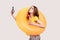 Funny female with brown wavy hair in yellow T-shirt holding orange rubber ring and making selfie at phone makes kiss gesture,