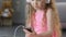 Funny female child listening to music in headset, holding smartphone, closeup