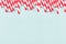 Funny festive bright abstract background - striped red cocktail straws on pastel candy mint color backdrop.