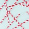 Funny festive bright abstract background - striped red cocktail straws on pastel candy mint color backdrop, pattern, square.