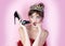 Funny fetish high heels. Pretty woman with crown holding shoe on pink. Gorgeous charming dreamy lady with surprised