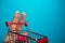 Funny fingers shopping at supermarket with red cart trolley on blue background