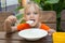 Funny five-year girl with pleasure eats porridge for breakfast