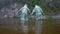 Funny flex in camouflage raincoats. Two teenagers perform synchronized dance moves in the rain, standing knee-deep in