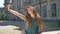 Funny ginger young woman doing different face expressions and smiling, taking selfie and standing on street