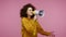 Funny girl afro hairstyle in hoodie talking with megaphone, proclaiming news, announcing advertisement, warning