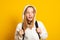 Funny girl dressed white hoodie on yellow  background with backpack. Portrait of cool schoolgirl with backpack