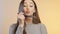 Funny girl grimaces and fooling around with a makeup brush on a colored studio background, young woman in a positive mood, female