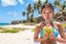 Funny girl having fun drinking coconut water on beach. Cute Asian woman doing goofy face sipping with straw on natural