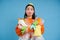 Funny girl holding lots of recycling garbage, plastic waste to recycle, blue background