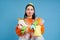 Funny girl holding lots of recycling garbage, plastic waste to recycle, blue background