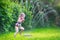 Funny girl playing with garden sprinkler