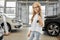Funny girl standing in auto salon and keeping car keys