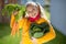 Funny girl with two pigtails in yellow smiling with fresh autumn harvest in sunny rural garden