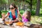 Funny girl and woman eating pasta salad from a plastic lunchbox in a table picnic in the country