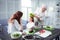 Funny grandmother having fun while putting some lettuce on head of girl