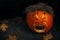 Funny halloween carved pumpkin into face expression, black background with copy space, creative squash carving for ghost night and