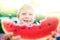 Funny handsome boy eating slice water melon