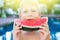 Funny handsome boy eating slice water melon