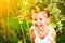 funny happy baby child girl in a wreath on nature laughing in summer