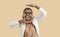 Funny happy black woman in suit and glasses smiling and dancing on beige background
