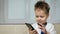 Funny and happy boy 3-4 years old communicates on a mobile phone. Little businessman